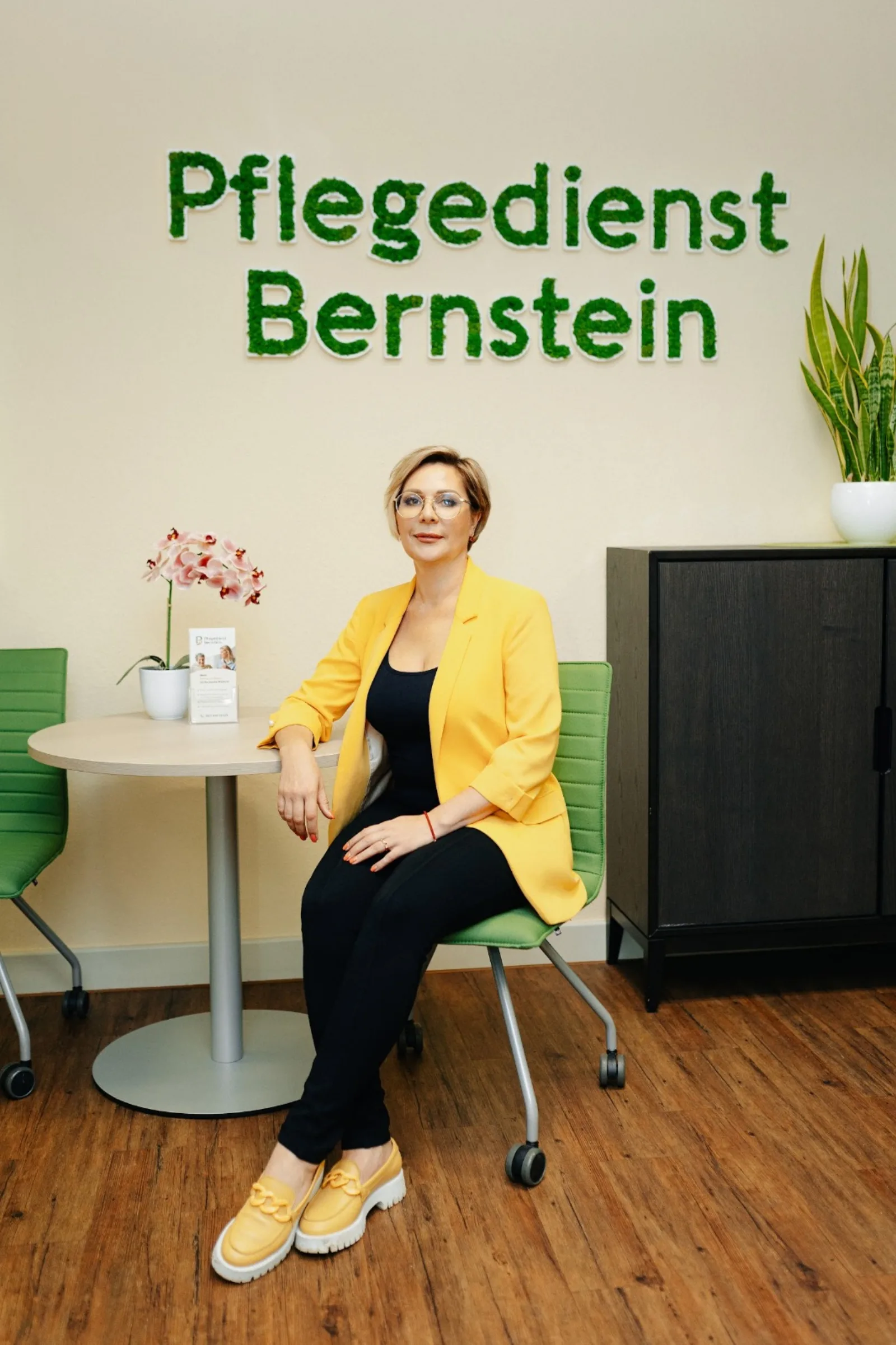 Geschäftsführerin des Pflegedienst Bernstein im Empfangsbereich unter dem Wandschriftzug Pflegedienst Bernstein